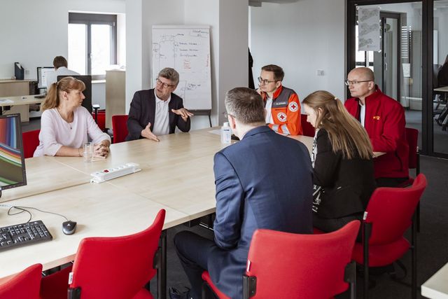 Menschen sitzen an einem Konferenztisch und sind ins Gespräch vertieft.