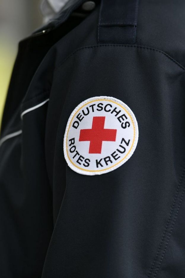 Symbolfoto: Eine dunkelblaue, modische Dienstjacke einer Führungskraft mit dem Rundlogo des DRK im Fokus