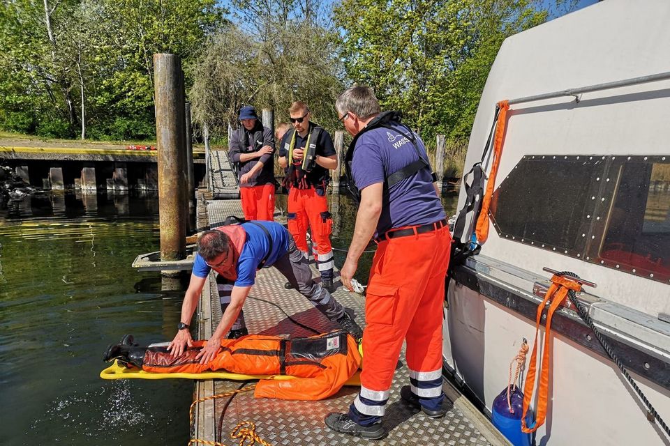 Einsatzkräfte der Wasserwacht trainieren die Übergabe einer Person am Steg