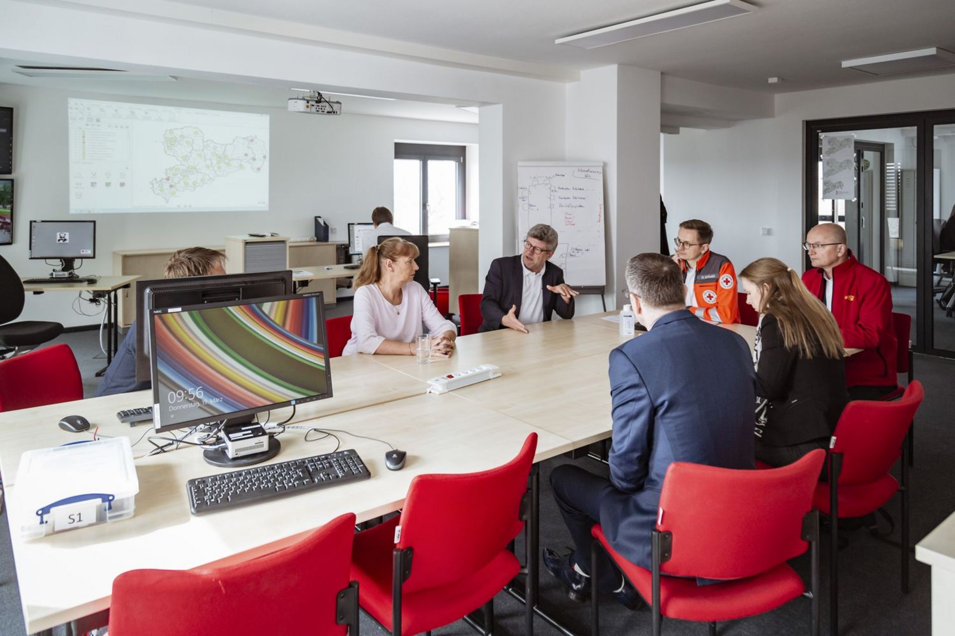 Menschen sitzen um einen Konferenztisch herum und sind ins Gespräch vertieft.