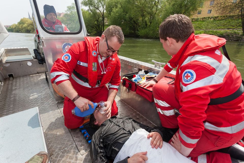 Einsatzübung, Helfer auf einem Motorboot der Wasserwacht auf der Donau leisten Erste Hilfe und beatmen eine aus dem Wasser gerettete Person